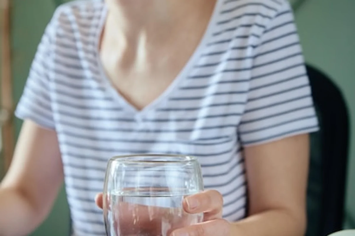 Kobieta pije wodę w domowym biurze - zdrowa opieka dla freelancerów