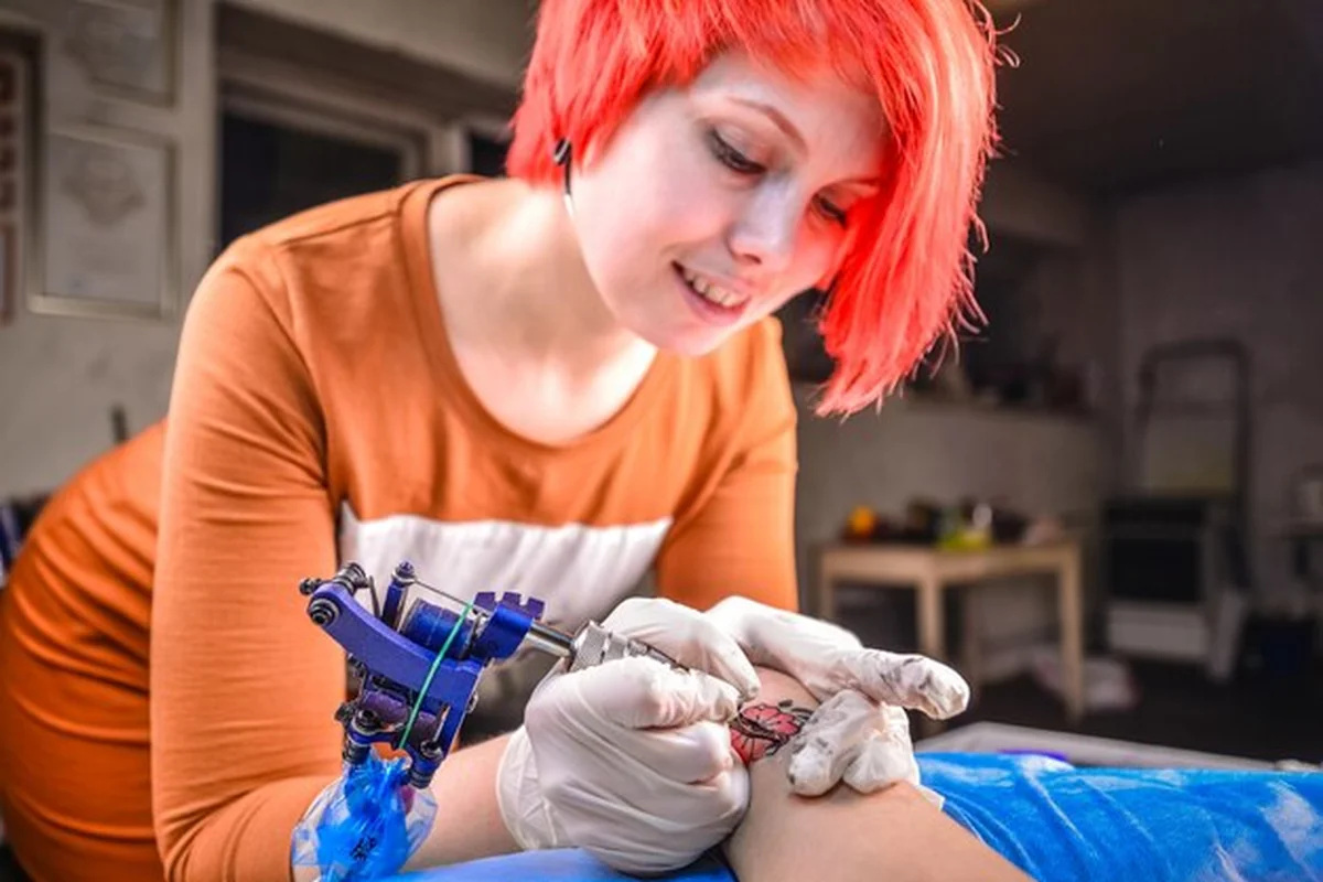 Profesjonalny tatuator wykonuje tatuaż na skórze w studio tatuażu. Pielęgnacja tatuażu dla zachowania koloru