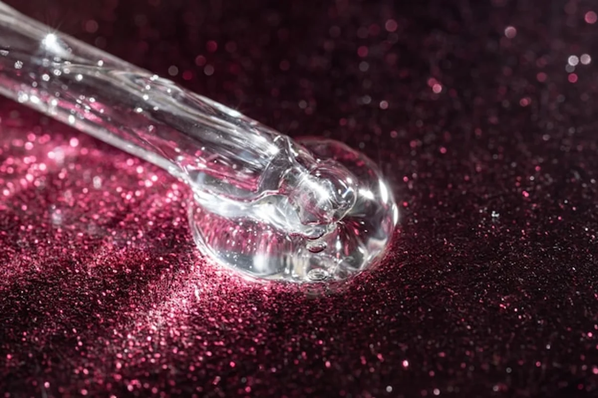 Pipeta z serum zawierającego kwas hialuronowy i kolagen na modnym różowym tle, nowoczesna pielęgnacja skóry