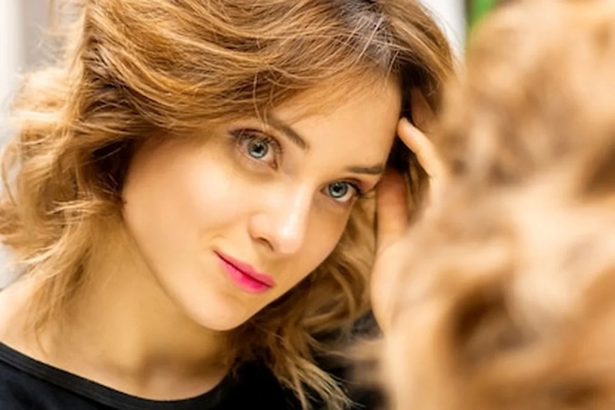 Piękna kaukaska kobieta patrzy na swoje odbicie w lustrze w gabinecie kosmetycznym