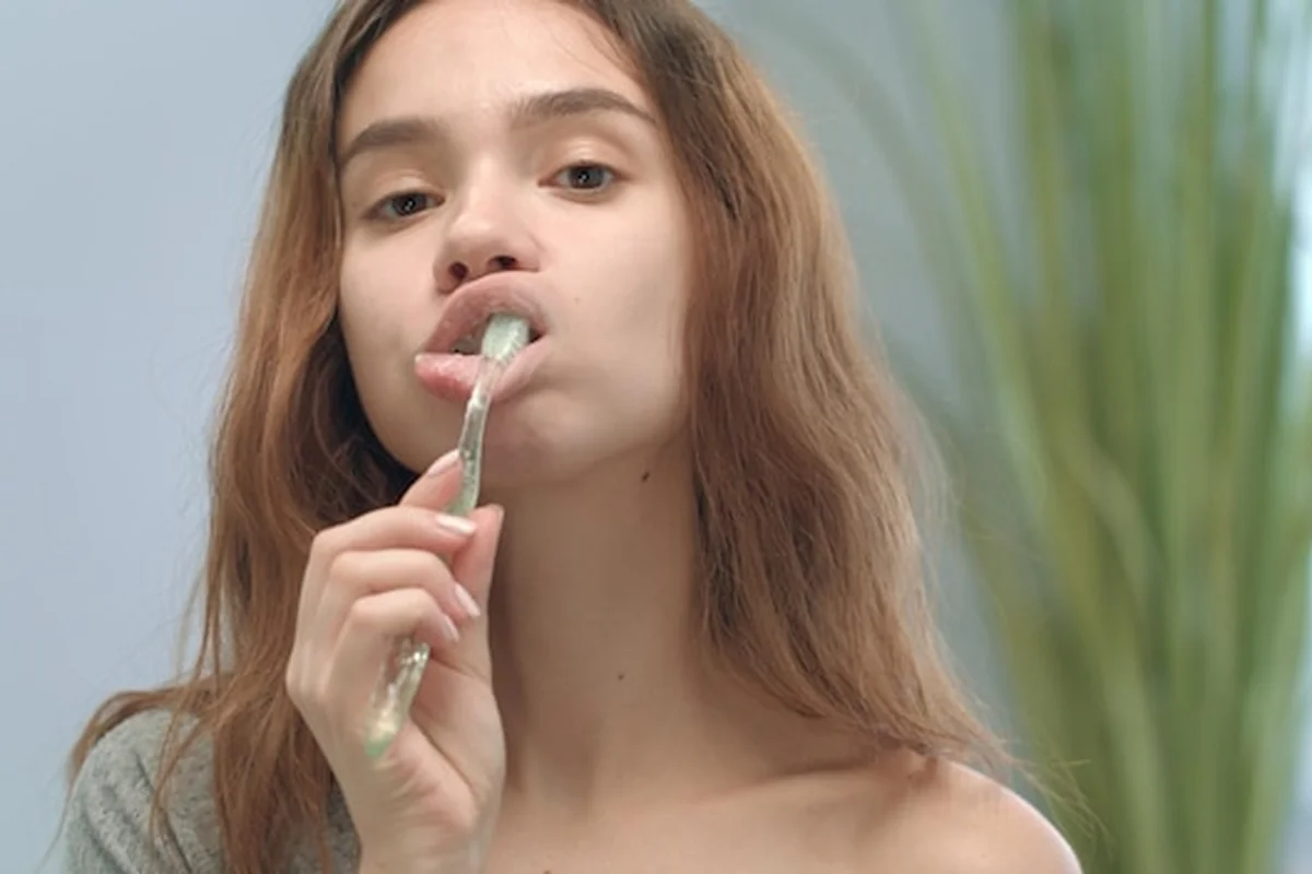 Kobieta masuje usta szczoteczką do zębów przed kamerą, odkryj skuteczne techniki masażu