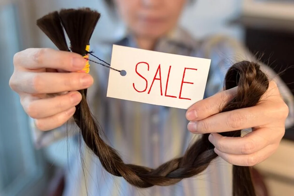 Długie brązowe włosy sprzedawane przez kobietę z etykietą. Metody, ceny i zalety przedłużania włosów