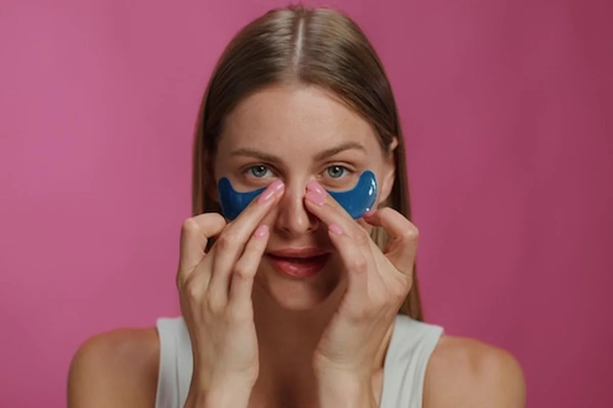 Kobieta nakłada plasterki na oczy w walce z workami pod oczami