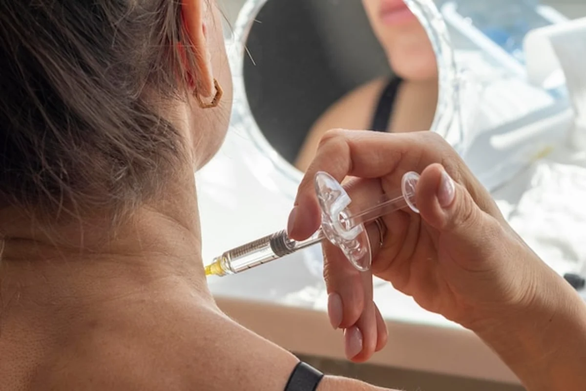 Kosmetyczka wykonuje mezoterapię na szyi i twarzy, łagodząc dyskomfort pacjentki