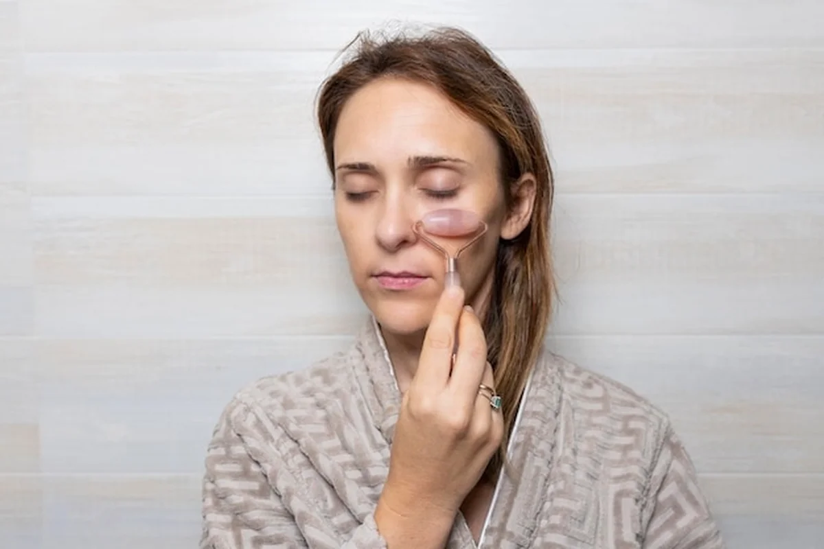 Kobieta masuje twarz kamieniem, zmniejszając worki pod oczami z masażerem higieny osobistej