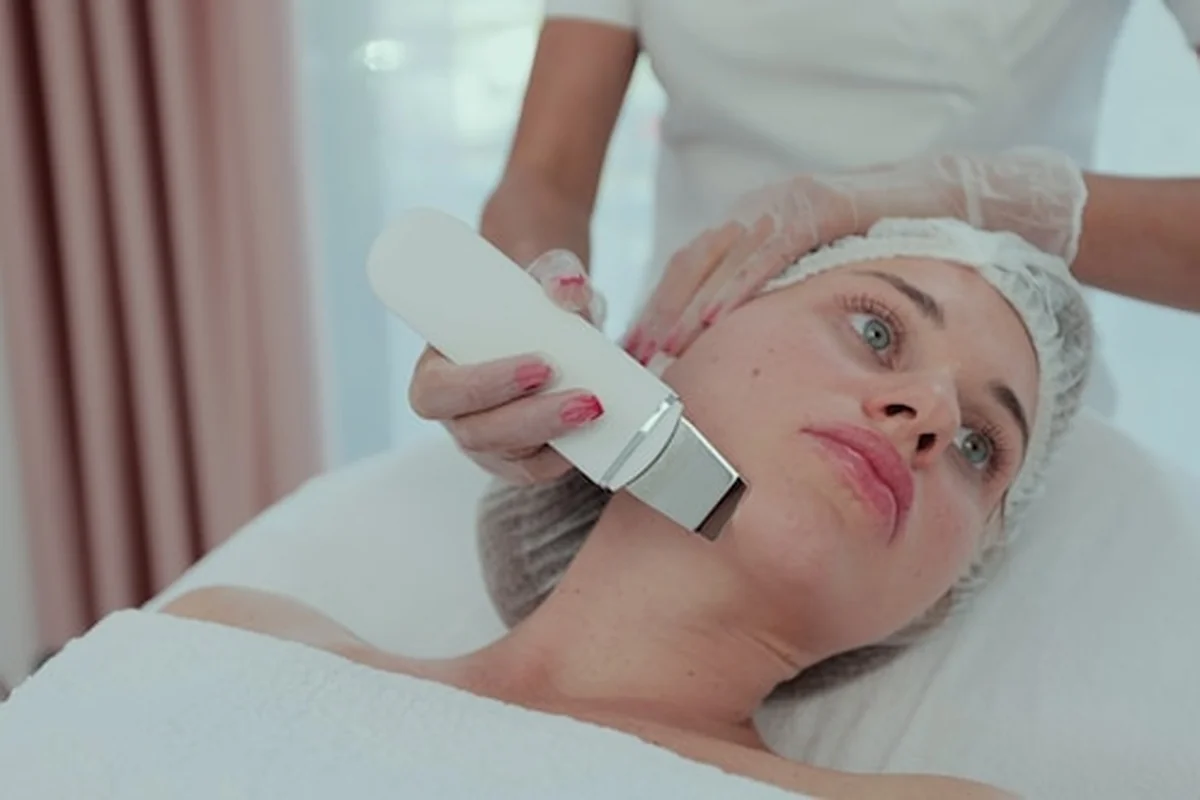 Kobieta otrzymuje peeling kawitacyjny USG twarzy - innowacyjna metoda oczyszczania skóry. Kosmetologia i pielęgnacja twarzy