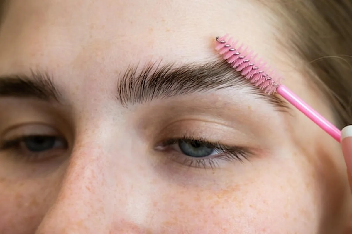 Mistrz stylizuje brwi klienta po laminacji brwi. Jakie są różnice między zabiegami?