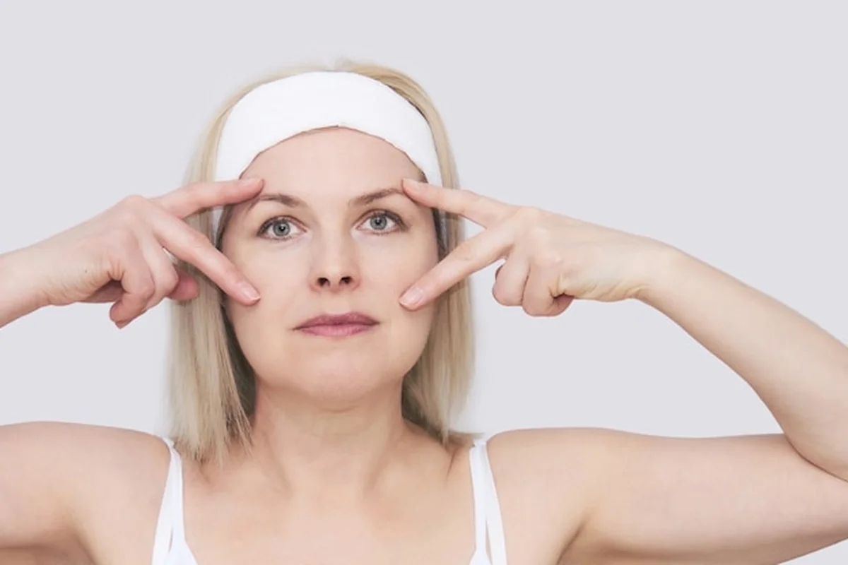 Kobieta w średnim wieku wykonuje automasaż twarzy wokół oczu, dbając o kondycję skóry i poprawę widzenia