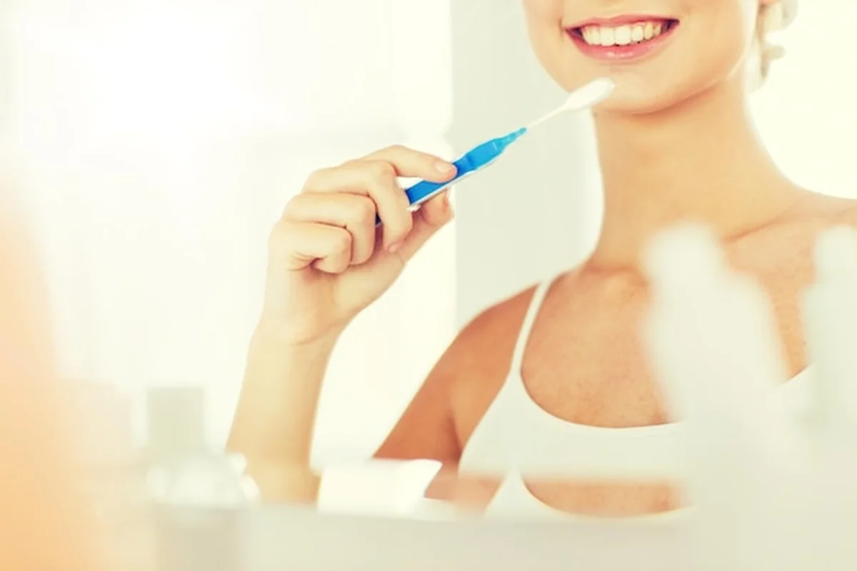 Zbliżenie uśmiechniętej kobiety czyszczącej zęby sodą oczyszczoną w domowej łazience