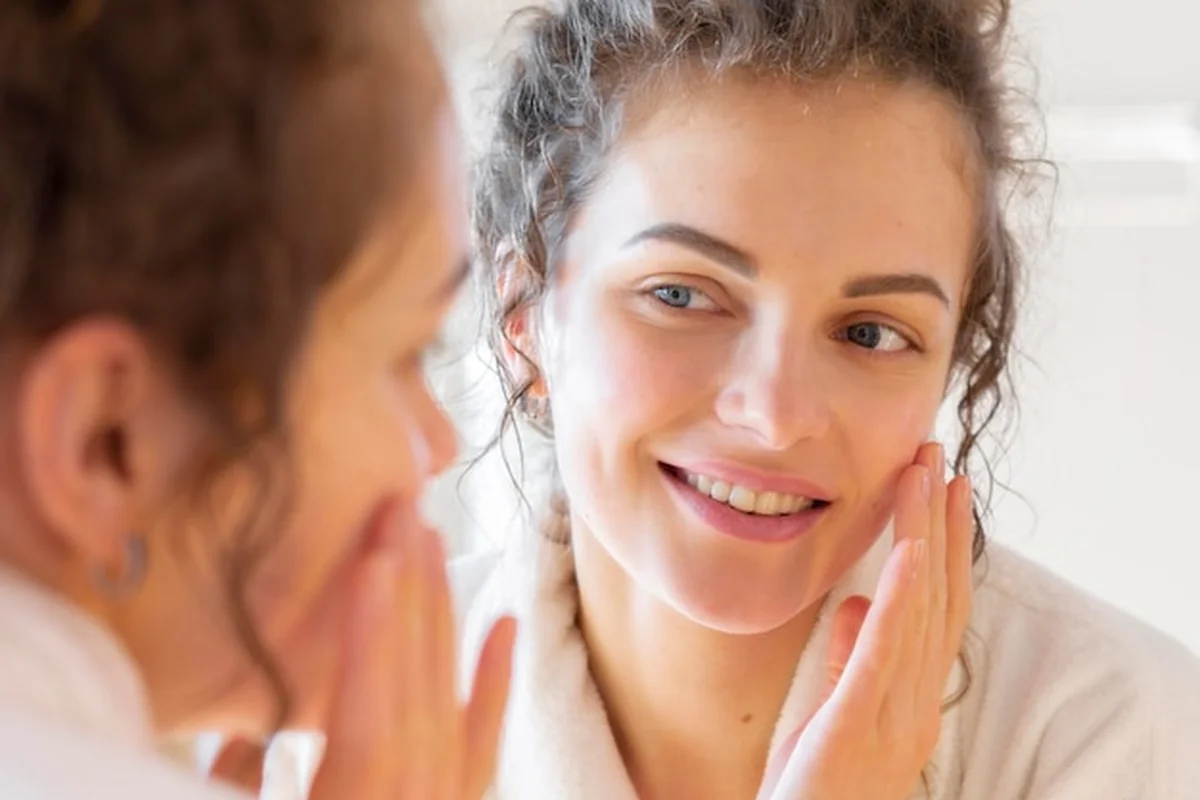 Kobieta nakłada krem na twarz, dbając o elastyczność skóry twarzy