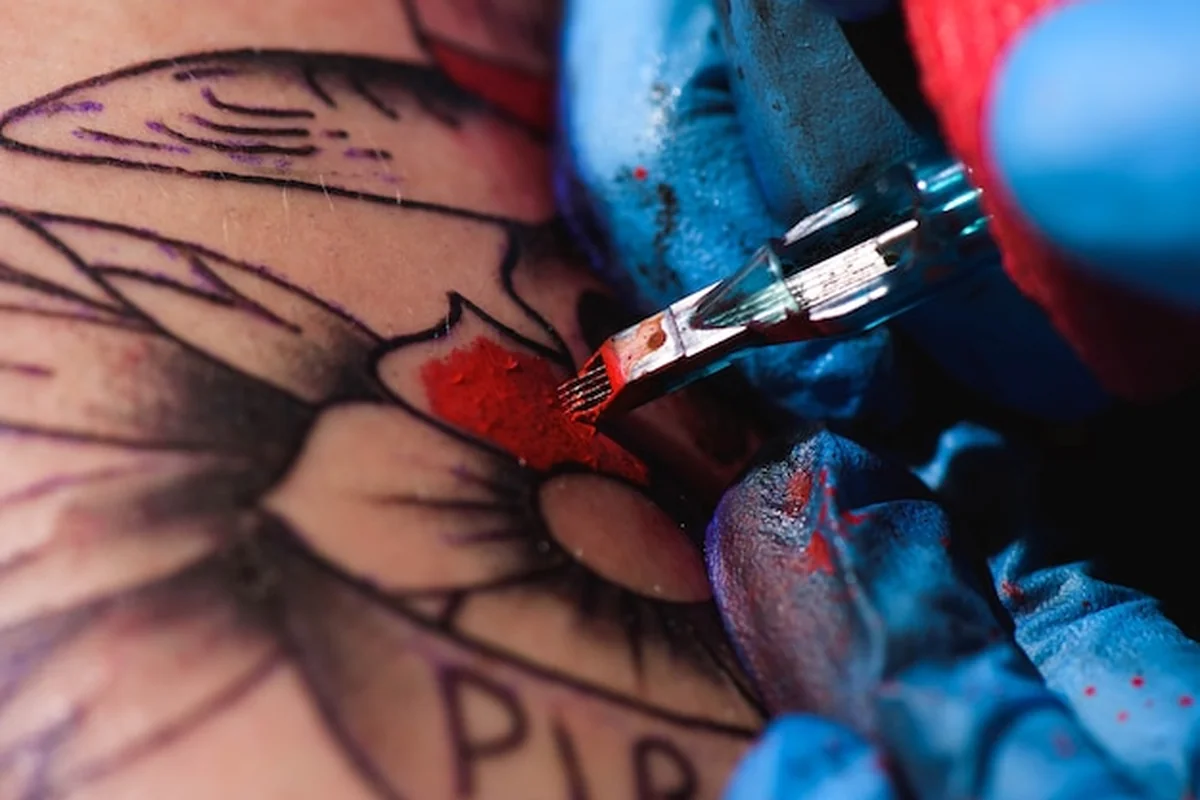 Proces tworzenia tatuażu z bliska, człowiek tworzący obraz pod ręką w salonie urodowy