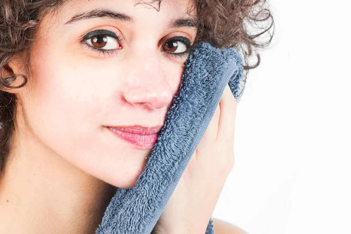 Młoda kobieta usuwająca wągry z nosa ręcznikiem, skuteczne sposoby na zaskórniki