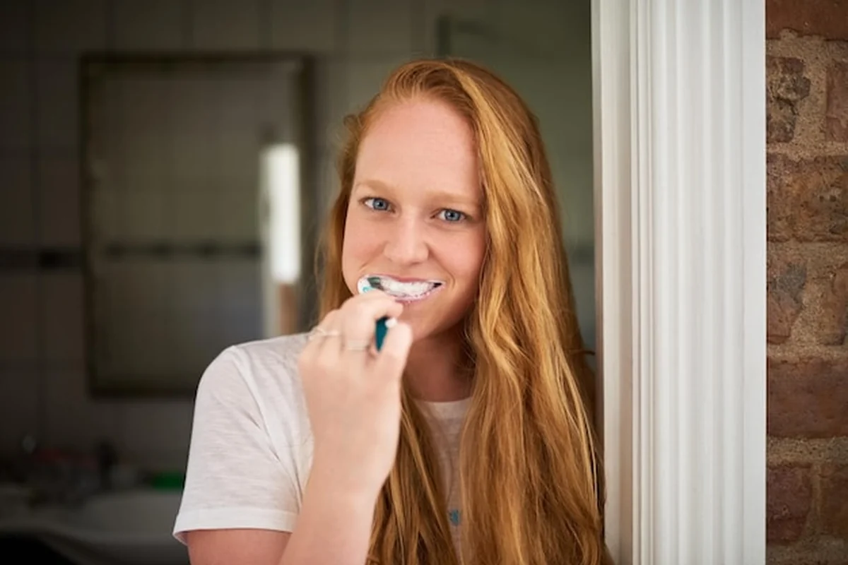 Kobieta szczotkująca zęby w łazience z pastą do zębów i szczoteczką dla higieny jamy ustnej