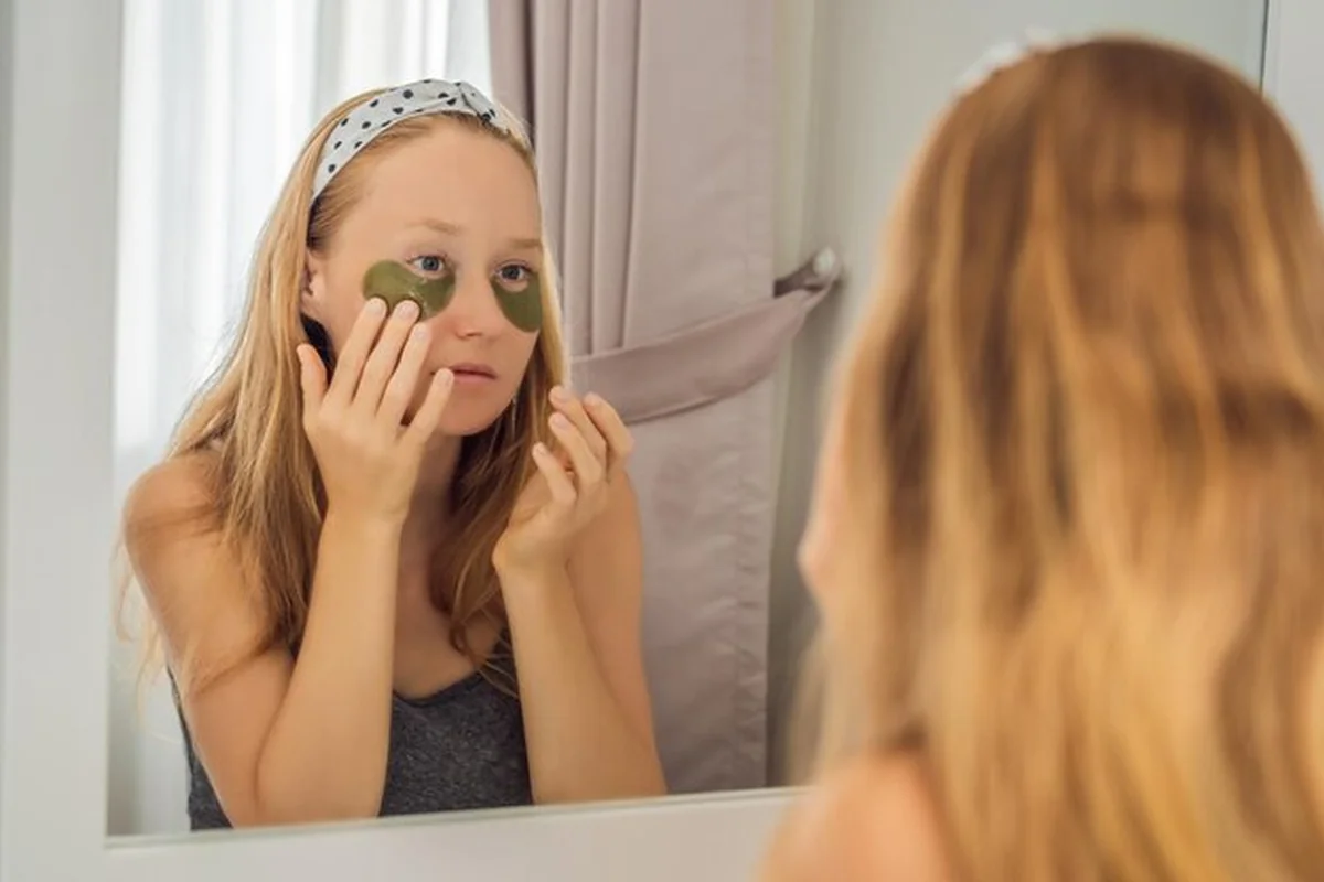 Uśmiechnięta kobieta z hydrożelowymi plastrami pielęgnacyjnymi, dbająca o skórę pod oczami